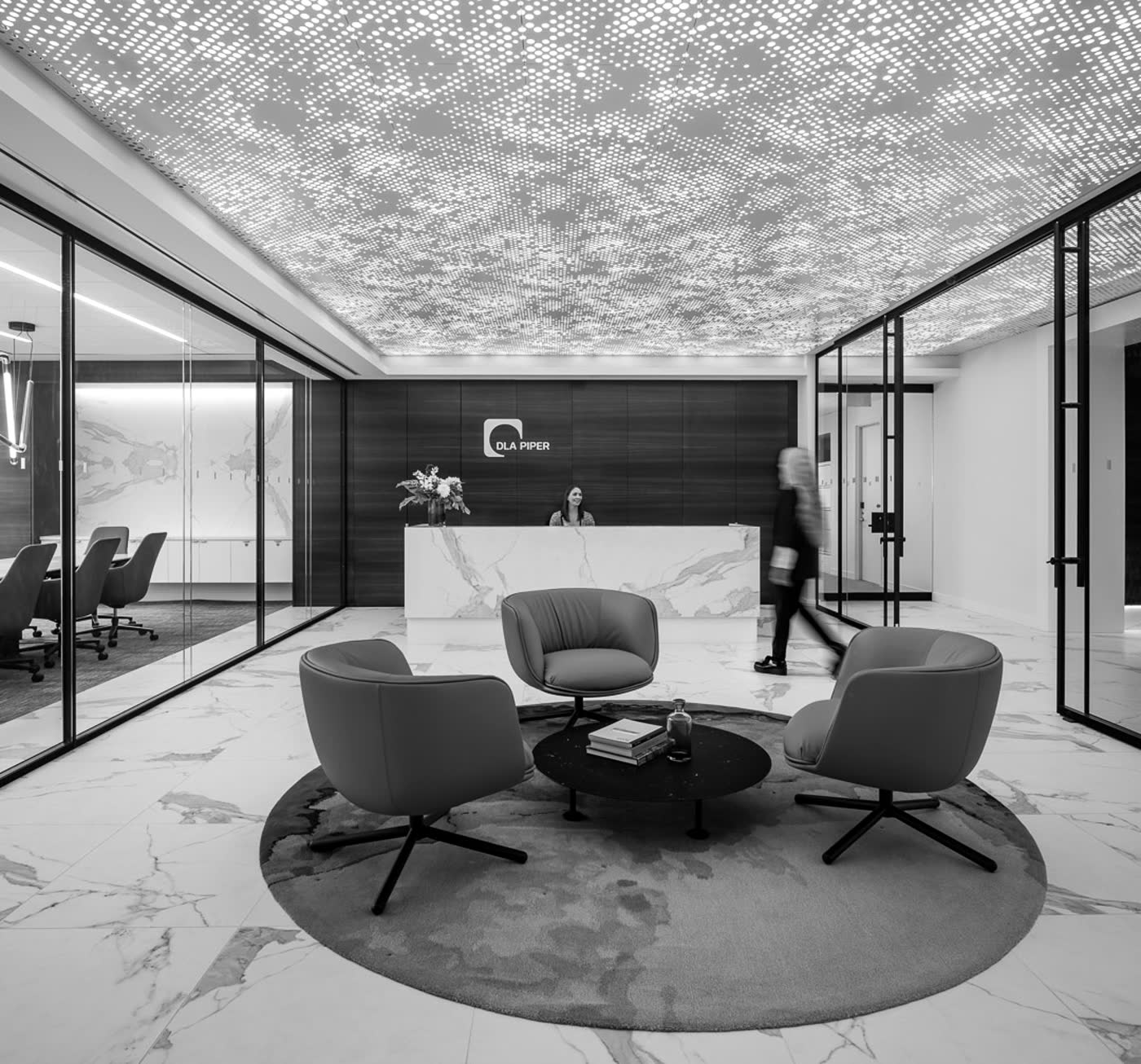 Reception with a perforated backlit ceiling over a white veined marble counter